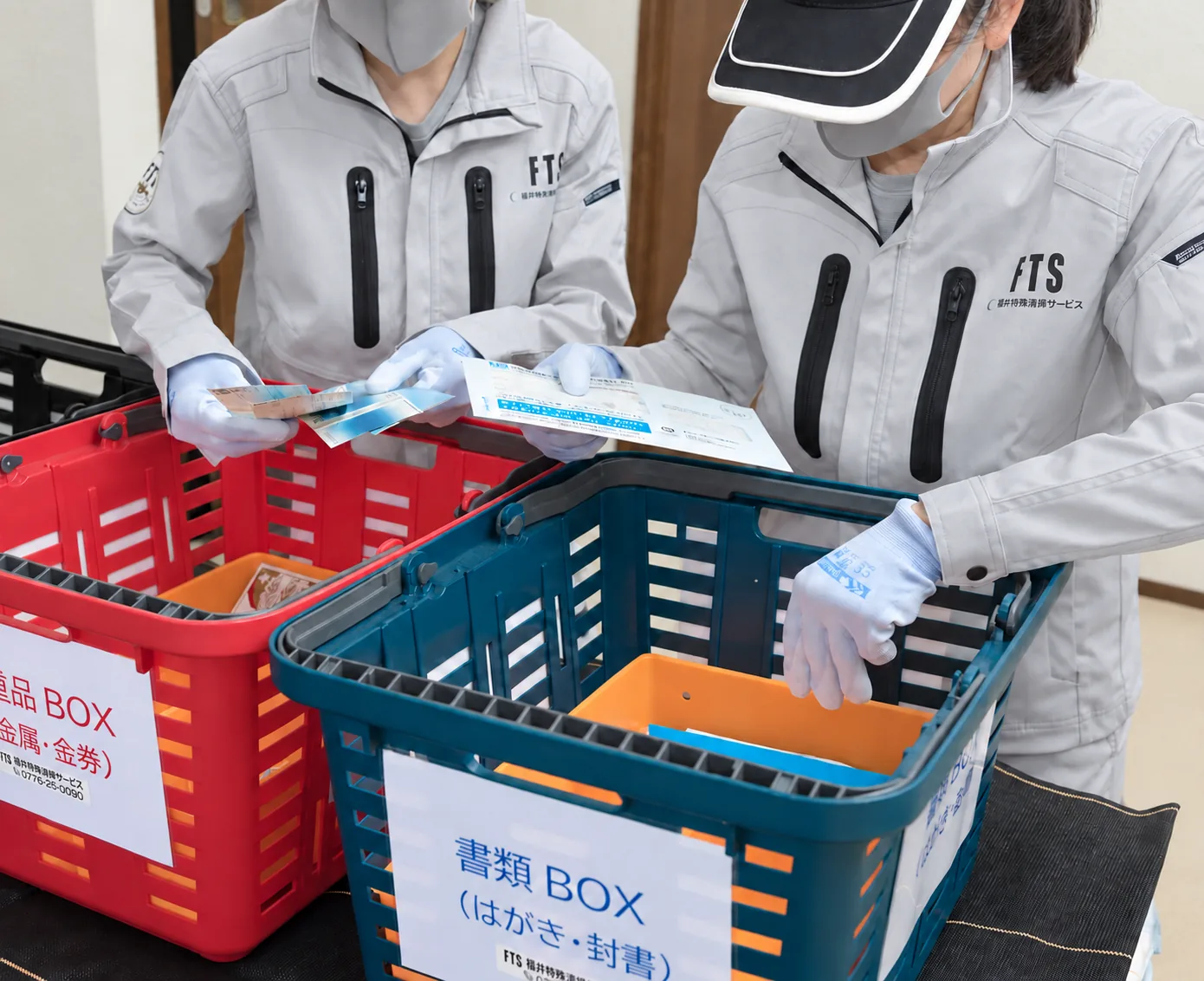 仕分け用のカゴで遺品を確認するスタッフ