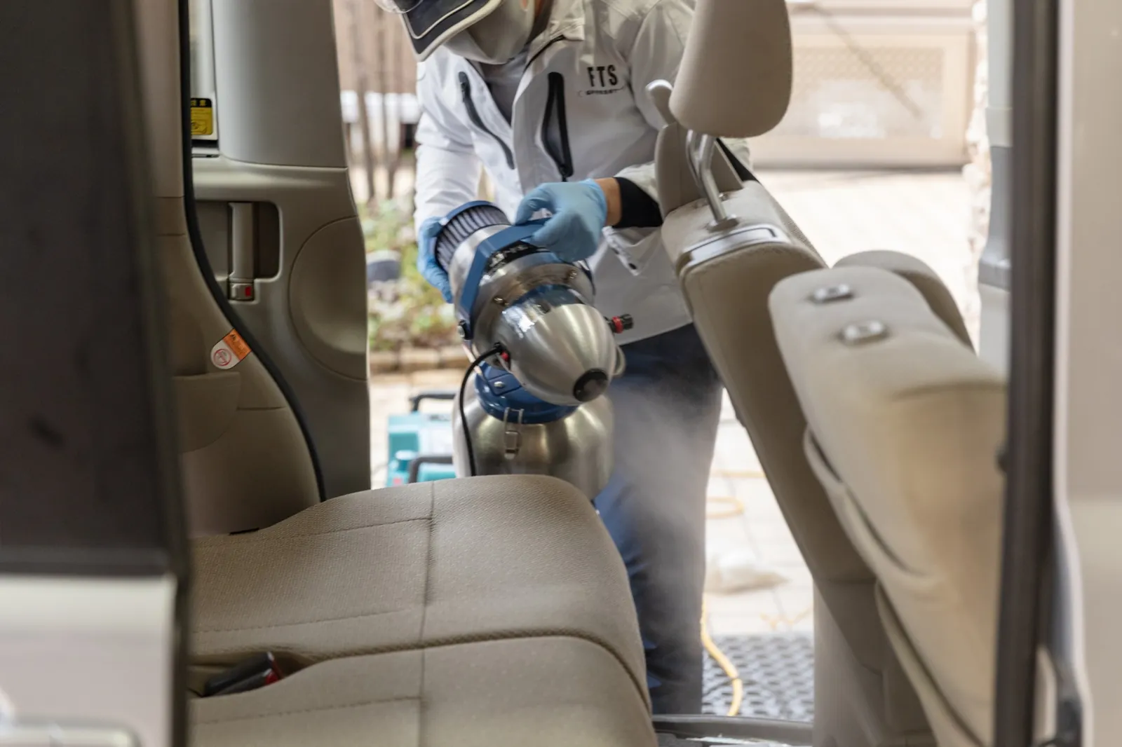 車内でスプレー機を使って消臭作業を行うスタッフ